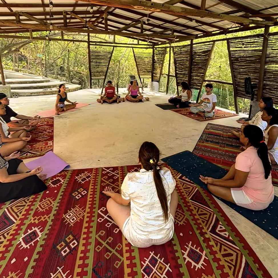 Clase de yoga en grupo, sentados en ronda bajo un techo de madera